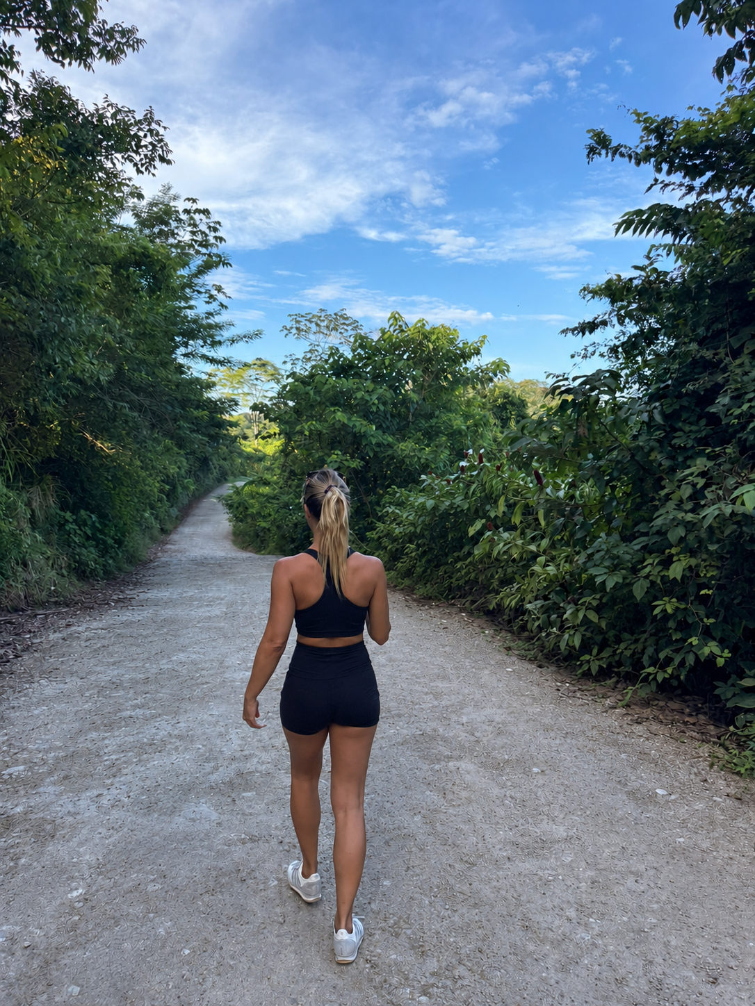 Lucía caminando de espaldas por un sendero rodeado de naturaleza